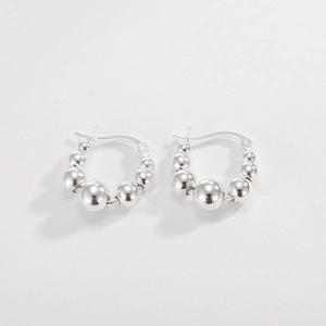 Détail des boucles d'oreilles créoles en argent 925 avec perles graduées et finition polie
