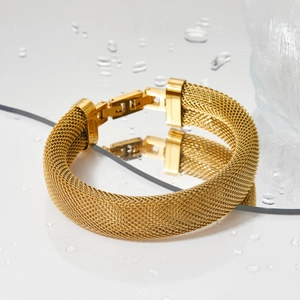 Macro shot of gold stainless steel mesh bracelet featuring detailed woven texture and clasp