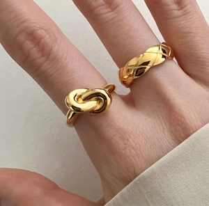Macro view of gold quilted pattern ring and knot ring set on model's hand