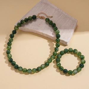 Close-up of green marble-textured acrylic beads with golden metal lobster clasp