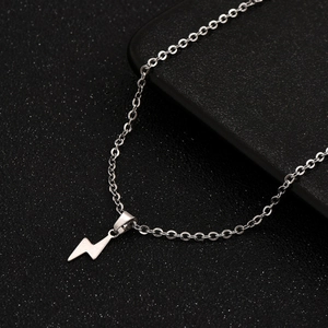 Minimalist stainless steel lightning bolt pendant necklace on dark textured surface