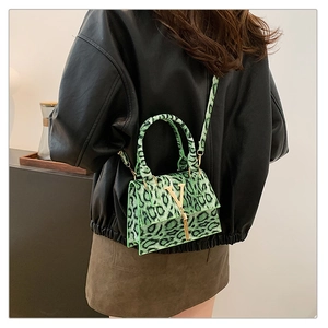 Dettaglio borsa leopardata verde con fibbia a V dorata e frange metalliche dorate