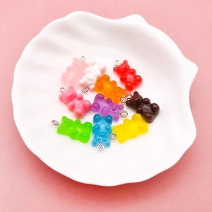 Close-up of colorful resin gummy bear charms with metal loops in a white shell dish