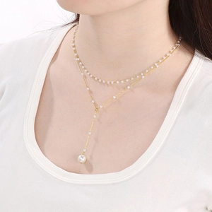 Detail of Y-shaped gold double layer necklace with small pearls and a large pearl tassel