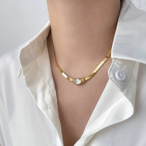 Close-up of golden herringbone snake chain necklace with water drop cubic zirconia on neck