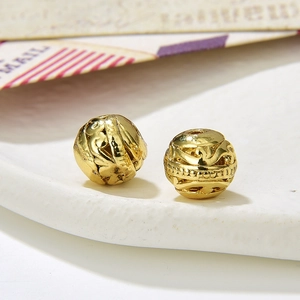 Macro shot of two vintage golden hollow round beads with detailed floral engravings for DIY jewelry