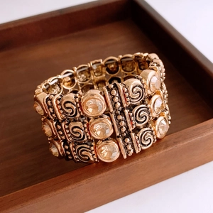 Close-up of vintage gold elastic bracelet with spiral textures and amber crystals