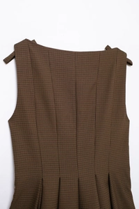 Detail shot of brown houndstooth dress fabric texture with shoulder strap and waist pleats