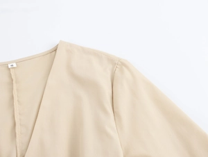 Gros plan détaillé du col en V et de l'étiquette de taille S sur une robe beige