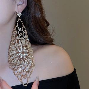 Macro shot of oversized gold waterdrop earrings with sparkling white crystals on model