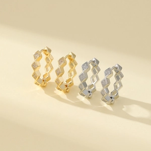Detailed close-up of geometric diamond-shaped gold and silver earrings with zircon inlay