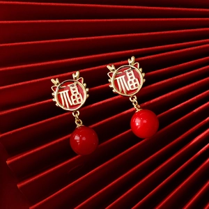 Close-up of Chinese New Year earrings with golden Fu character and red beads
