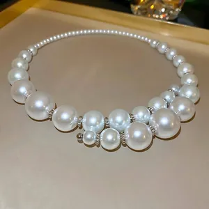 Elegant geometric pearl necklace with varied sizes and silver beads in a luxury tray