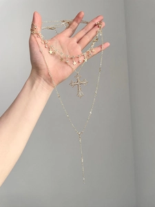 Close-up of gold-plated triple necklace set with star charms and cross pendant details