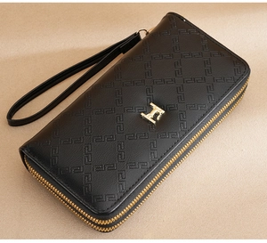 Detalle de cartera larga de cuero con doble cremallera y correa de muñeca dorada