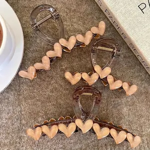 Three premium heart-shaped hair claws in cream and brown resin with gold springs