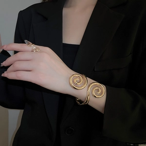 Detailed view of polished gold spiral open cuff bracelet and matching ring on model