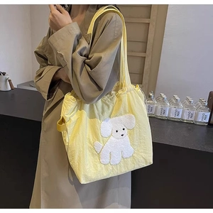 Detailed view of yellow canvas tote bag featuring a cute white puppy plush patch detail