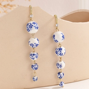 Macro shot of blue and white porcelain beads with golden tassels and rhinestone details