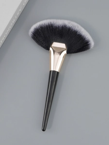 Detail of a large fan brush with black and white gradient bristles and gold metal ferrule