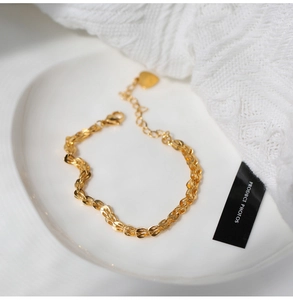 Dettaglio del bracciale vintage in oro 18K con ciondolo a cuore su piatto di ceramica