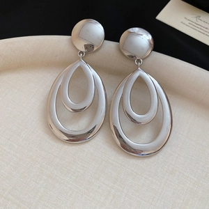 Détail macro de boucles d'oreilles argentées avec double goutte d'eau creuse en métal poli