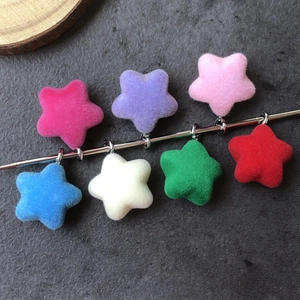 Detailed macro view of seven colorful flocked star pendants with metal loops and soft texture