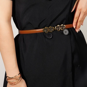 Detail of adjustable brown skinny belt with golden rose buckle on black dress