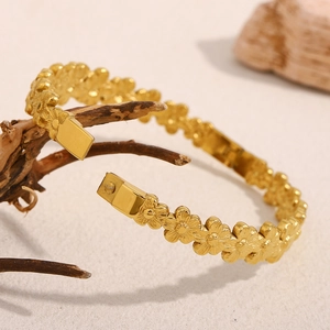 Eleganter 18K vergoldeter Edelstahl Armreif mit Gänseblümchen auf natürlichem Holzhintergrund