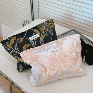Detailansicht der Jacquard-Blumenstickerei und Goldrelief-Textur auf Kosmetiktaschen