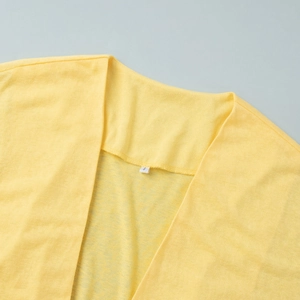 Close-up of bright yellow lightweight knit cardigan collar and size S label detail