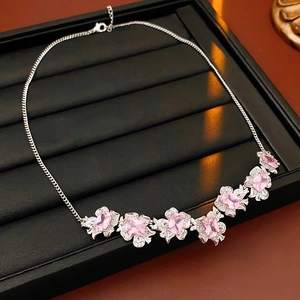 Macro shot of a floral necklace with pink oval gemstones and sparkling crystals on a tray