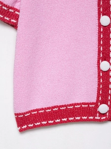 Detailed macro view of pink knit fabric with red ribbed trim and white contrast stitching
