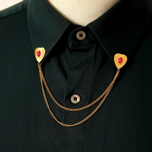 Dettaglio della spilla da colletto a cuore dorato con pietre rosse su camicia nera