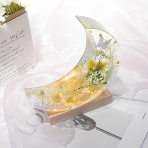 Moon-shaped resin mold ornament with dried flowers and butterfly on a wooden base