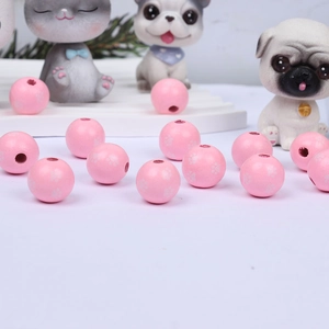 Macro detail of pink round wooden beads with white paw prints for DIY jewelry crafting