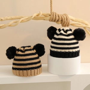 Dettaglio di berretti in maglia a righe per bambini con doppi pompon in finta pelliccia