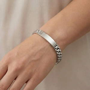 Close-up van een zilveren roestvrijstalen horlogebandarmband met een blanco ID-plaatje.