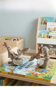 Detail van twee konijnenbeeldjes van hars in speelse poses op boeken in een kinderkamer