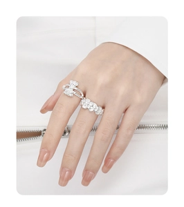 Detailed view of silver bow-knot and floral rings worn on fingers with minimalist style