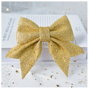 Detail of glittery gold ribbon bow ornament resting on white star-patterned mesh