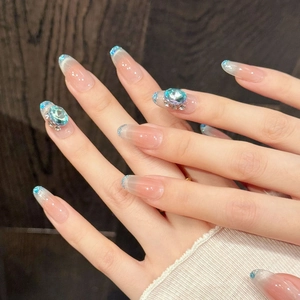 Close-up of almond-shaped press-on nails with pink to blue gradient and luxury crystal gems