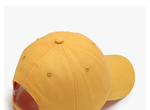 Detail of a mustard yellow cotton baseball cap with ventilation eyelets and top button