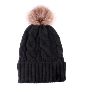 Close-up of black cable knit beanie texture with large fluffy faux fur pompom detail