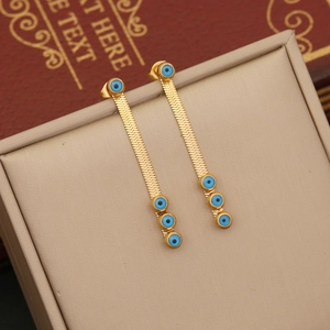 Golden snake chain earrings with blue evil eye pendants on a jewelry box background