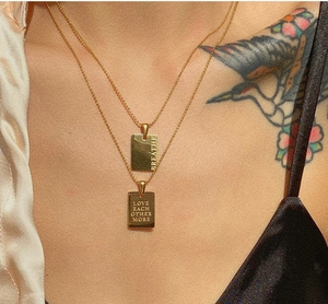 Gold double-layered stainless steel necklace with engraved rectangular pendant on model