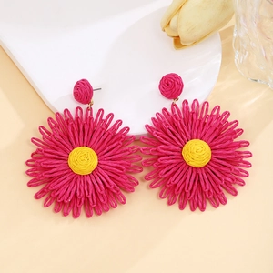 Detail of handmade raffia flower earrings in bright magenta and yellow bohemian style