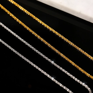 Glistening silver and gold titanium steel neck chain necklaces on reflective black surface