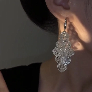 Detail view of silver hollow diamond fringe earrings worn by a model in profile