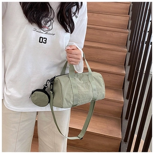 Close-up of a light green cylindrical handbag with matching round coin purse on a wooden staircase